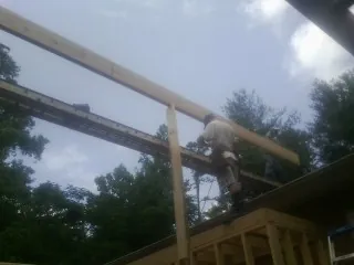 Carpenter setting a ridge beam over a new addition frame — Ice Dam Removal by Roofing Brothers in Inkom