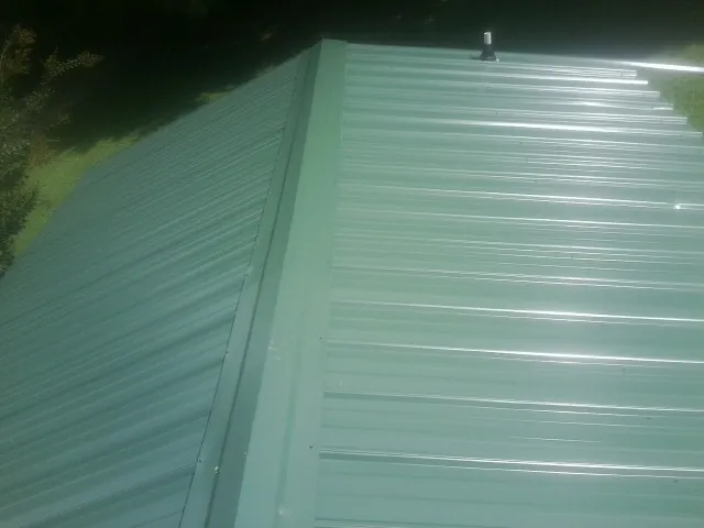 New green metal panels meeting at the ridge of a roof — Flat Roof Repair work by our crew in Inkom