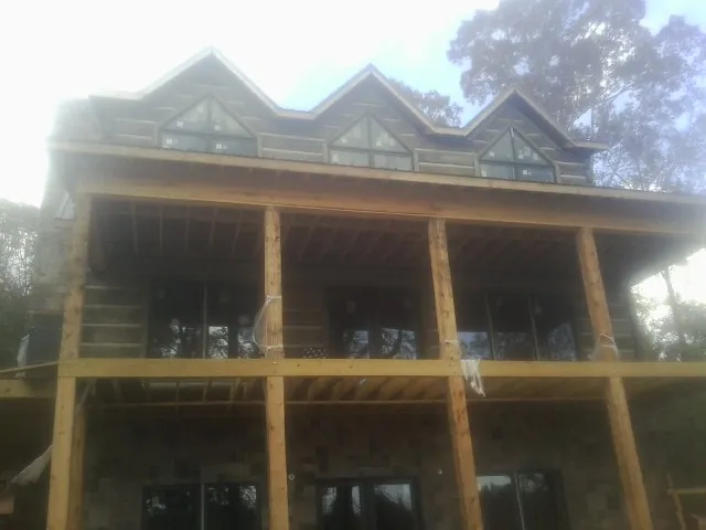 Dormers and porch framing on a large log home under construction — Roof Coating work by our crew in Inkom