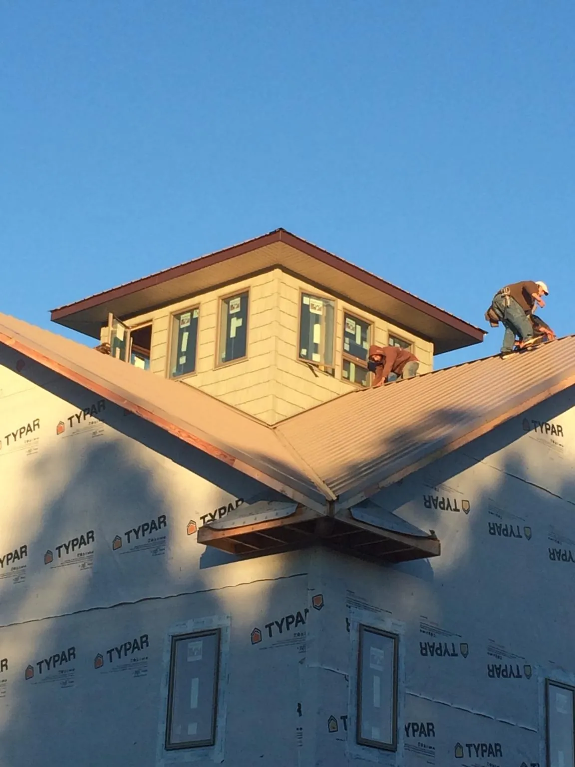 Roofers working around a rooftop cupola on a new metal roof at sunset — Roof Waterproofing in Inkom by Roofing Brothers